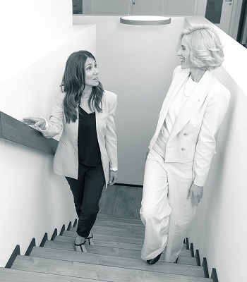 Zwei Geschäftsfrauen unterhalten sich freundlich auf einer Treppe.