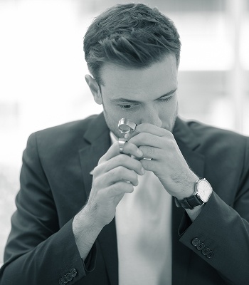 Mann betrachtet aufmerksam ein Edelmetallstück mit einer Lupe.